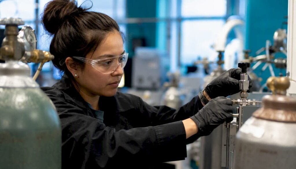 Scientist adjusting helium gas flow valve in lab